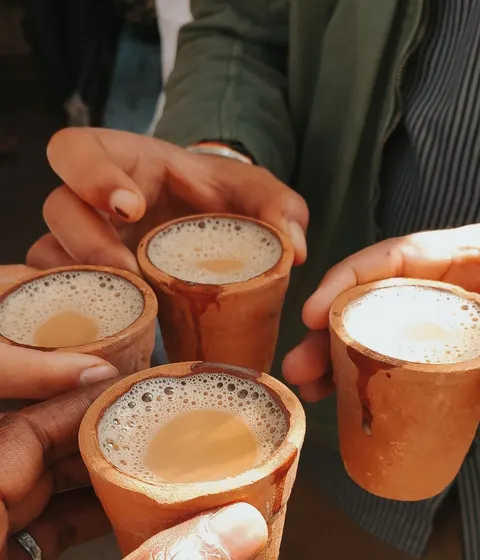 Friends raising clay cups of chai together in India