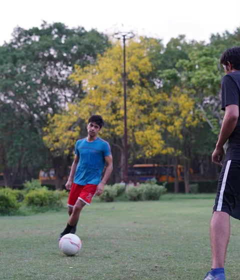 Friends playing a casual football game on a field in India