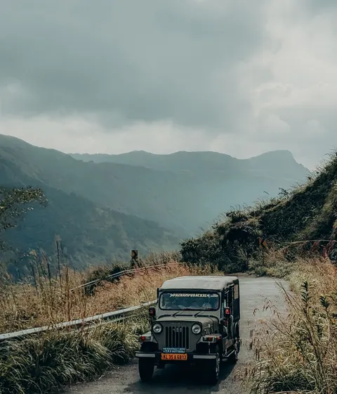 A jeep on a winding hillside road in Kerala